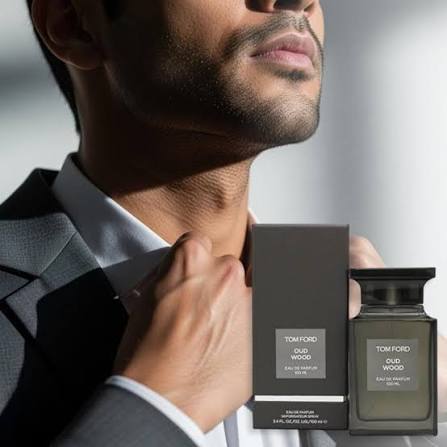 Man holding Tom Ford Oud Wood perfume bottles against a neutral background
