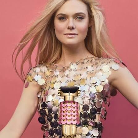 Woman holding a decorative perfume bottle against a pink background