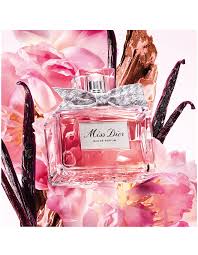 Miss Dior Pink perfume bottle with a silver bow and cap, surrounded by pink flowers and vanilla beans.