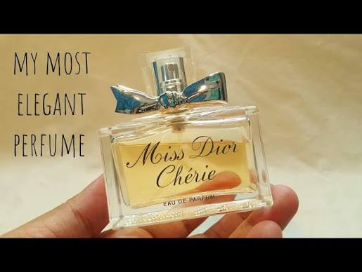 A hand holding a bottle of Dior Miss Dior Chèrie Eau de Parfum, with text on the left reading 'MY MOST ELEGANT PERFUME'.