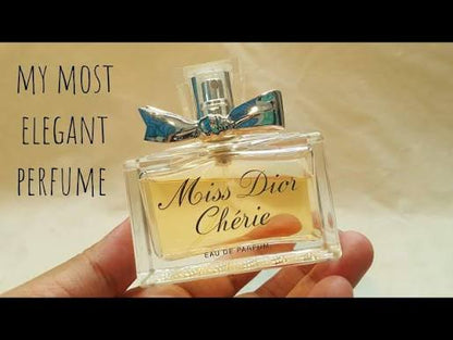 A hand holding a bottle of Dior Miss Dior Chèrie Eau de Parfum, with text on the left reading 'MY MOST ELEGANT PERFUME'.