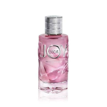 Dior Joy Eau de Parfum in a pink faceted glass bottle with a textured silver cap, shown on a white background with a soft reflection.