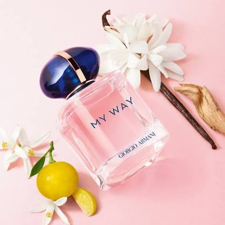 Perfume bottle labeled 'My Way' by Giorgio Armani with flowers and lemons on a pink background