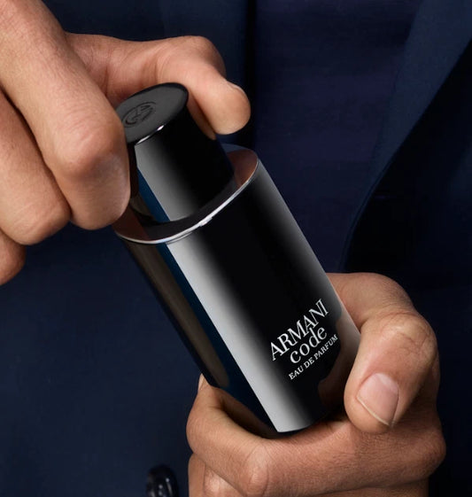 Hand holding an Armani Code perfume bottle against a dark background