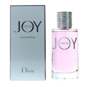 Dior Joy Eau de Parfum bottle with pink liquid next to its silver box packaging, featuring the Dior logo.